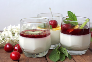 three desserts Panna cotta with KIWI cherry and mint on wooden surface