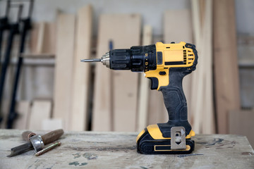 A modern black and yellow screwdriver on a wooden table, tools on workshop