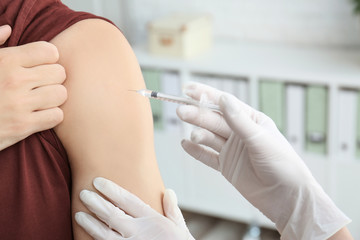Obraz na płótnie Canvas Doctor vaccinating male patient in clinic, closeup