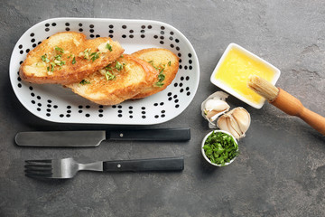 Plate with delicious homemade garlic bread on table