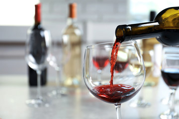 Pouring delicious red wine into glass on table