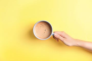 Young woman with cup of delicious hot coffee on color background, top view