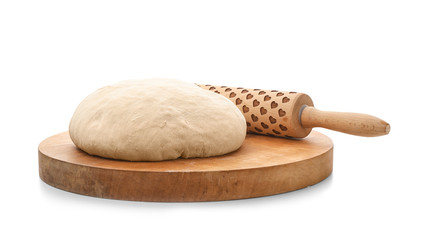 Wooden board with raw wheat dough and rolling pin on white background