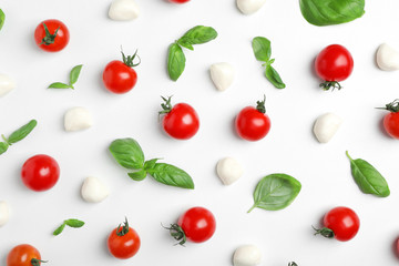 Flat lay composition with tomatoes, mozzarella cheese balls and basil on light background