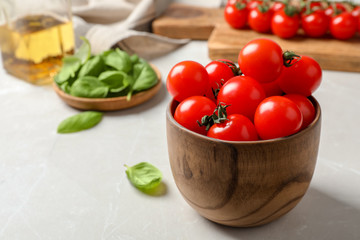 Bowl with ripe red tomatoes and basil on table