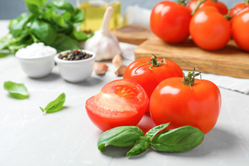 Ripe red tomatoes and basil on table