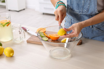 Young woman squeezing juice in bowl for lemonade on table, closeup. Natural detox drink