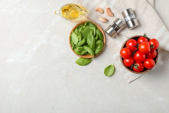 Flat lay composition with tomatoes, oil and basil on light background
