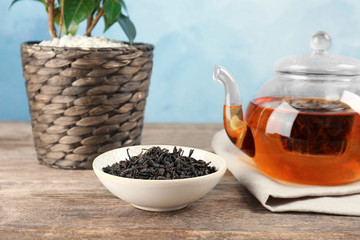 Bowl with dry tea and glass pot of hot beverage on table