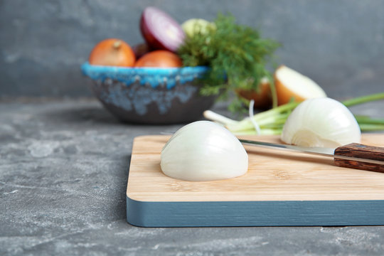Wooden board with cut onion on table