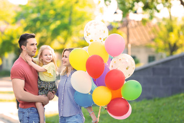 Fototapeta na wymiar Happy family with colorful balloons in park on sunny day