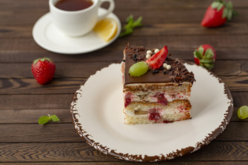 Delicious cake with strawberries, grapes, chocolate, tea with lemon