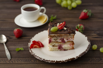 Delicious cake with strawberries, grapes, chocolate, tea with lemon