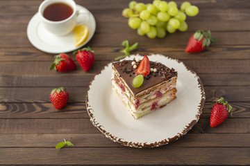 Delicious cake with strawberries, grapes, chocolate, tea with lemon