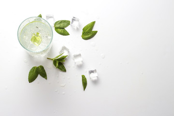 Glass with a refreshing drink with mint and ice on a light background. Flat lay, top view
