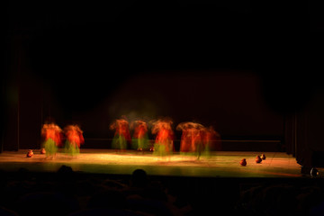 A group of people dancing on stage against dark black