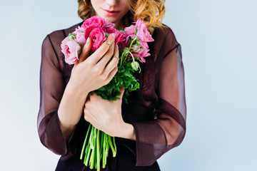 cropped shot of beautiful young woman holding tender pink flowers isolated on grey