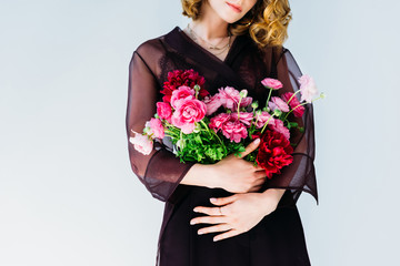 cropped shot of elegant stylish woman holding tender pink flowers isolated on grey
