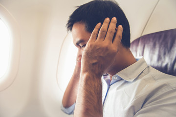 Male passenger having ear pop on the airplane - obrazy, fototapety, plakaty