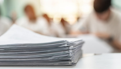 Exam answer sheet or application paper blurry view on table in examination room with blur education background of school university students taking exam test writing answer in seat row with stress