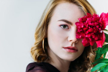 Fototapeta premium close-up view of girl holding red flower and looking at camera isolated on grey