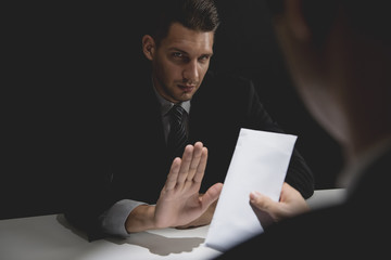 Businessman rejecting money in white envelope offered by his partner in shadow, anti bribery and...