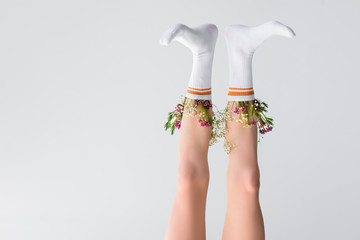 upside down view of female legs with flowers in socks isolated on grey