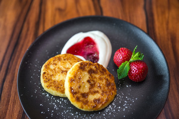 Cottage cheese pancakes. Russian syrniki with cranberry jam and yogurt, selective focus