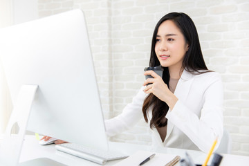 Young beautiful Asian woman drinking coffee at work