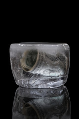 Money froze in the ice. The concept of freezing money deposits. Foreign bank account. Isolated on a black background.