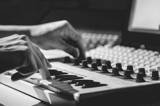 black and white musician hands playing midi keyboard in sound studio, recording concept