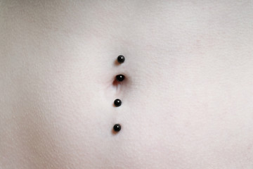 close-up of belly button or navel pierced with double barbell piercing