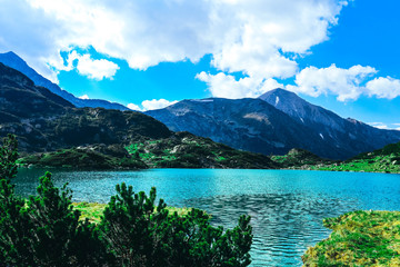 Beautiful alpine lake, river in the high mountains peak, blue sky background. Amazing Mountain hiking paradise landscape, summertime.