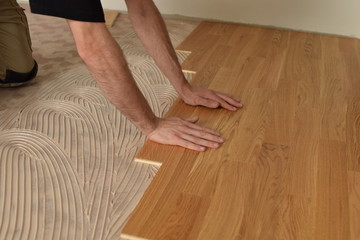 close up of worker installing wood parquet