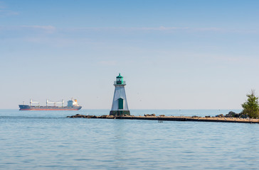 Fototapeta na wymiar Lighthouse and a freight ship