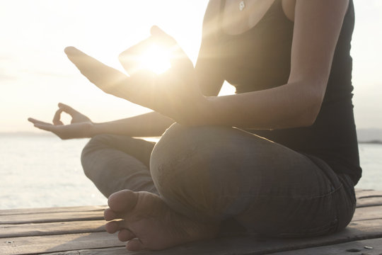 hands of woman meditating on a yoga pose on the beach