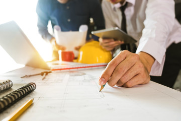 Two colleagues discussing data working and tablet, laptop with on on architectural project at construction site at desk in office