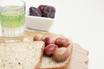 Ramadan Kareem celebration with islamic date, olive, glass of water, bread foods on white background