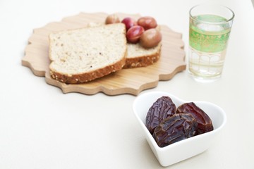 Ramadan Kareem celebration with islamic date, olive, glass of water, bread foods on white background