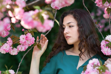Naklejka premium beautiful girl posing near sakura flowers