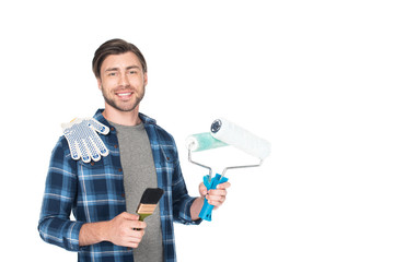 young smiling man with paint rollers, protective gloves and paint brush isolated on white background