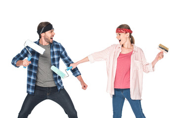 side view of screaming couple in headbands fighting by paint rollers isolated on white background
