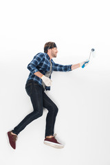 side view of smiling man in headband with paint roller isolated on white background