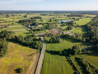 Naklejka premium drone image. asphalt road surrounded by pine forest and fields from above