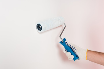 cropped image of man in protective glove painting wall in white by paint roller