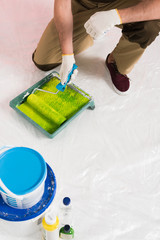cropped image of man in protective gloves dipping paint roller into roller tray