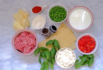 Ingredients for preparation of lasagna with pork forcemeat, green peas and tomatoes.