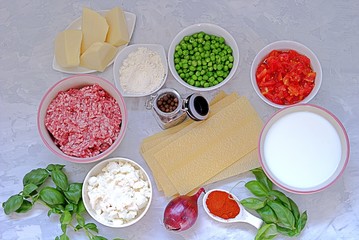 Ingredients for preparation of lasagna with pork forcemeat, green peas and tomatoes.