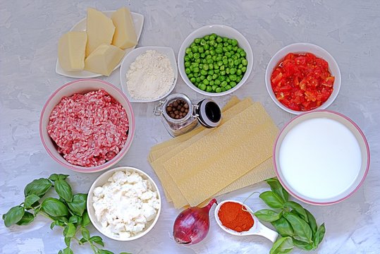 Ingredients for preparation of lasagna with pork forcemeat, green peas and tomatoes.