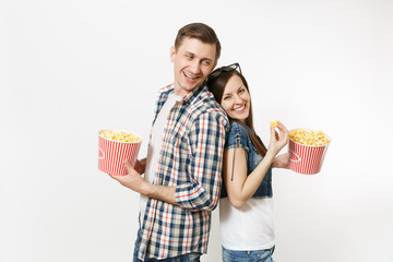 Young happy smiling couple, woman and man in 3d glasses and casual clothes watching movie film on date, holding buckets of popcorn, eating isolated on white background. Emotions in cinema concept.